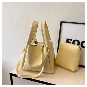 Detail of lychee textured leather bucket bag and matching zipper pouch in cream yellow