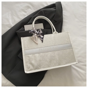Detailed macro view of the jacquard texture and silk scarf handle on this chic tote bag