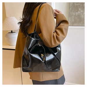 Dettaglio di una grande borsa tote in vernice nera con finitura lucida sulla spalla