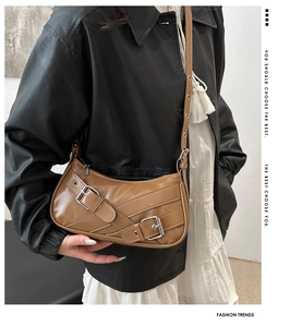 Detail of brown vintage biker shoulder bag featuring adjustable silver metal buckles