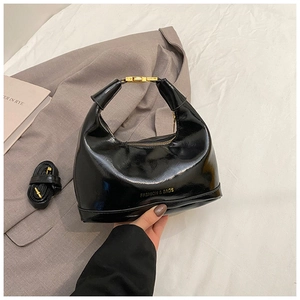 Detail of glossy black patent leather handbag with golden lock and adjustable strap