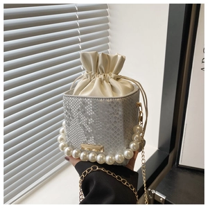 Detail of silver snake skin bucket bag with pearl handle and metal chain strap