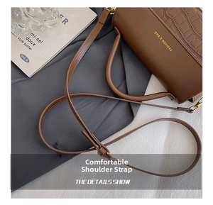 Detail of adjustable strap and crocodile texture on brown faux leather handbag