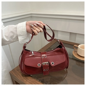 Detail of dark red faux leather underarm bag with silver buckles and eyelets