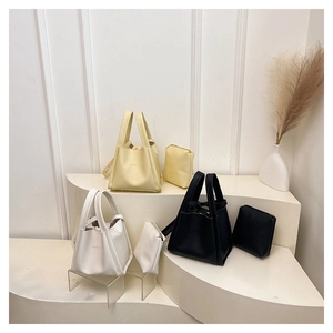 Three minimalist bucket bags in cream, white and black with matching square pouches