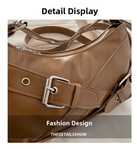 Close-up of brown glossy leather bag showing silver metal buckles and stitched detail
