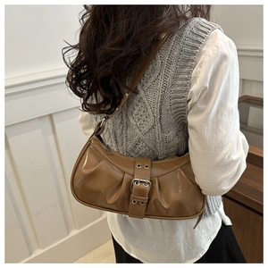 Detailed view of brown wrinkled leather texture and metallic buckle strap on shoulder bag