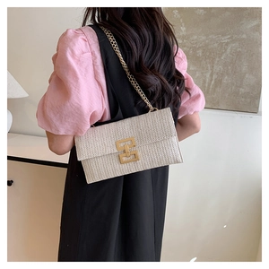 Detail of a beige woven crossbody bag with gold chain strap and square metal lock