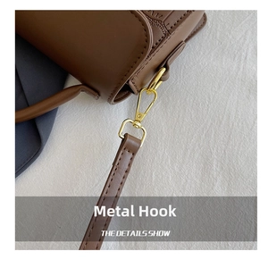 Close-up of premium brown stone-textured leather bag with shiny gold metal hardware hook