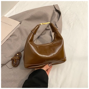 Detailed view of brown glossy leather hobo bag with gold hardware and shoulder strap