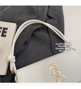 Detail showing the white leather knotted handle and golden metal logo on the handbag