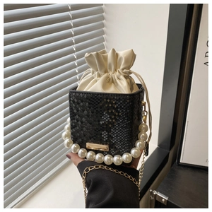 Detail of black snake pattern bucket bag with pearl handle and golden chain strap
