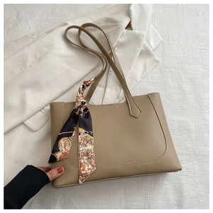 Détail du sac cabas en cuir kaki avec une poignée décorée d'un foulard en soie vintage