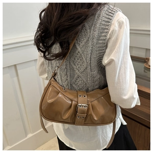 Detail of brown pleated shoulder bag with silver buckle and glossy patent finish