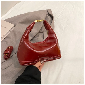 Macro view of burgundy hobo bag details with oil wax finish and gold metal buckles