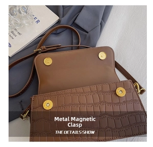 Detail shot of the crocodile embossed leather flap and dual golden magnetic closures