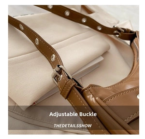 Detail of adjustable shoulder strap with silver eyelets on a brown underarm bag