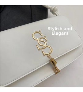 Detail of white leather crossbody bag with golden S-buckle and tassel pendant