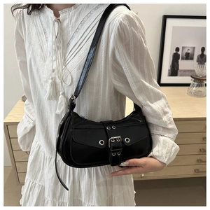 Close-up of black half-moon underarm bag with punk metal eyelets and belt buckle detail