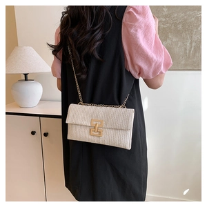 Dettaglio borsa a busta intrecciata beige con catena in metallo dorato e fibbia quadrata