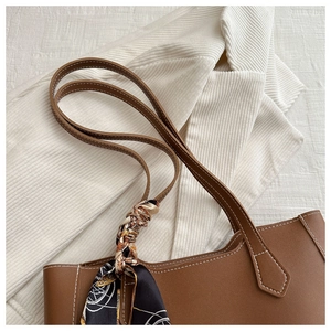 Détail du sac cabas en cuir marron avec surpiqûres blanches et foulard en soie au manche