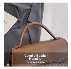 Detail shot of caramel brown faux crocodile texture with elegant handle and gold buckle
