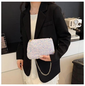 Détail d'une pochette à paillettes blanches avec chaîne dorée tenue par un mannequin