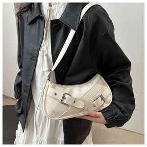 Detail of white patent leather shoulder bag with silver buckle straps and glossy finish