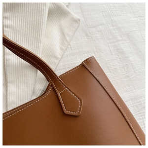 Détail du cabas en cuir marron avec surpiqûres blanches contrastées et texture premium