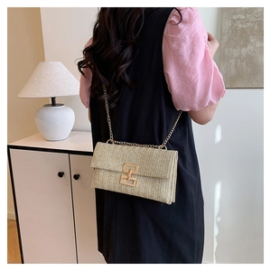 Dettaglio della trama intrecciata beige e catena dorata sulla borsa a spalla