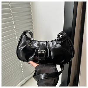 Close-up of black patent leather hobo bag featuring silver buckle and metal eyelets