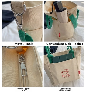 Detailed close-up of green straps, silver hooks, and zipper on off-white canvas bag
