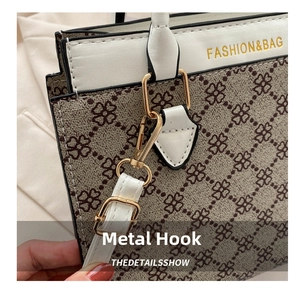 Detailed macro view of the gold-tone hardware hook and white leather strap of the handbag