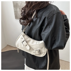 Close-up of a white crescent shoulder bag with metallic double buckle straps and glossy leather