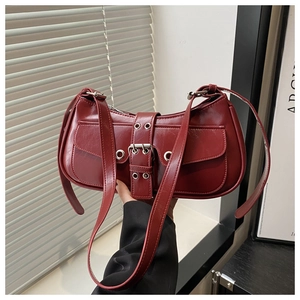 Detail of dark red vintage leather shoulder bag with silver buckle and glossy finish