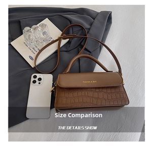 Detail of brown croc-effect flap bag with gold lettering and smartphone for size scale