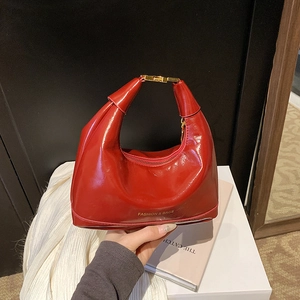 Glossy red patent leather dumpling handbag with gold clasp on white display box