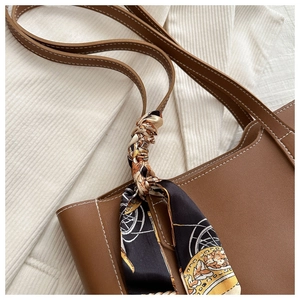 Détail du cabas en cuir marron avec surpiqûres blanches et foulard en soie au manche