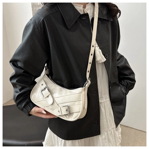 Detail of white glossy crescent shoulder bag with silver buckles on leather straps