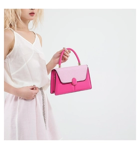 Detail of structural pink crossbody bag featuring color-block flap and golden hardware