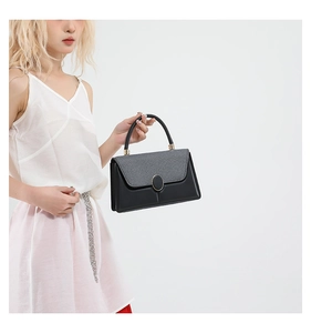 Detail view of contrast material handbag with grey fabric flap and gold hardware buckle