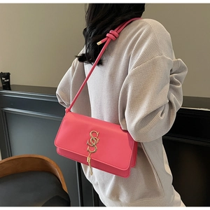 Close-up of pink leather crossbody bag featuring gold metal logo and stylish tassel