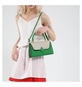 Detail shot of green crossbody bag with gold textured flap and metal clasp closure