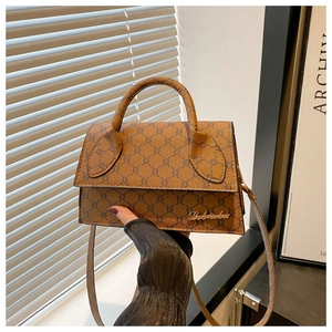 Détail du sac à main vintage marron avec monogramme, logo doré et texture en similicuir