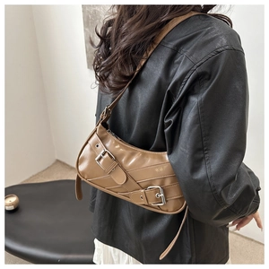 Detail of brown crescent shoulder bag with metallic buckles and retro biker style straps