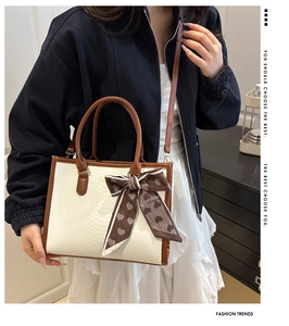 Detail of white crocodile texture tote bag with brown leather handles and heart print scarf