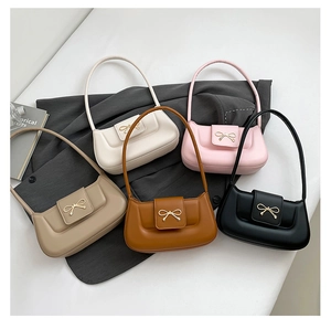 Top view of five colorful bow-accented shoulder bags arranged on a grey blazer
