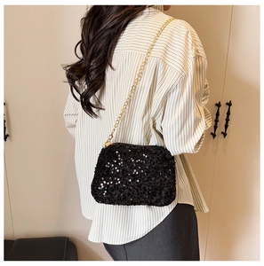 Vue détaillée d'un sac bandoulière en paillettes noires avec chaîne dorée sur mannequin