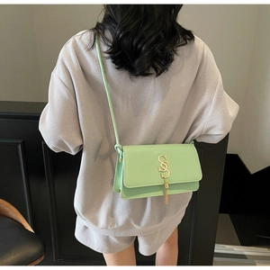 Detail view of a pale green crossbody bag with a gold S-letter buckle and stylish tassel
