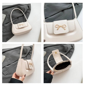 Detail view of cream white baguette bag with golden bow buckle and interior zipper pocket
